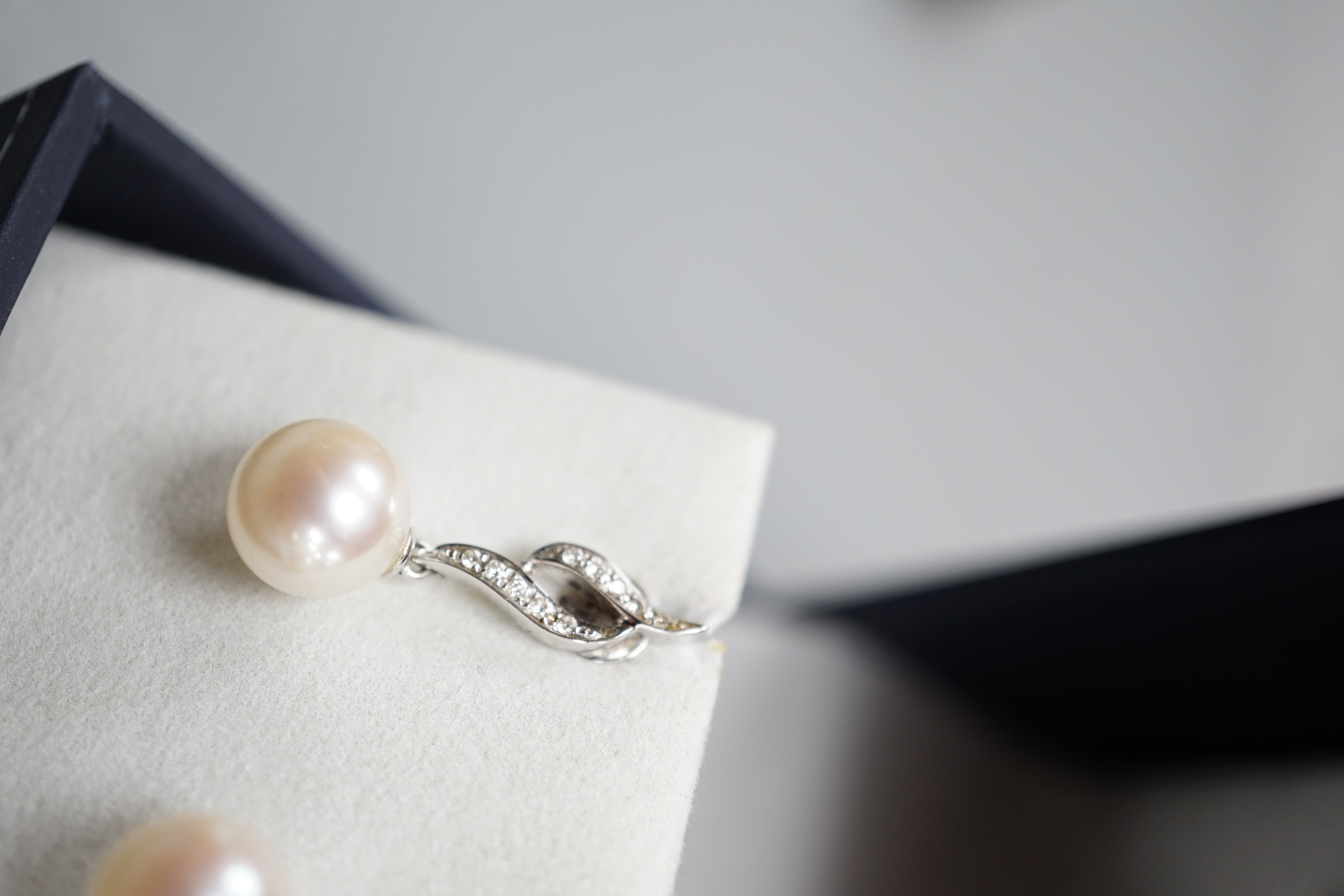 A modern pair of 14k white metal, cultured pearl and diamond set drop earrings, 24mm, gross weight 3.8 grams.